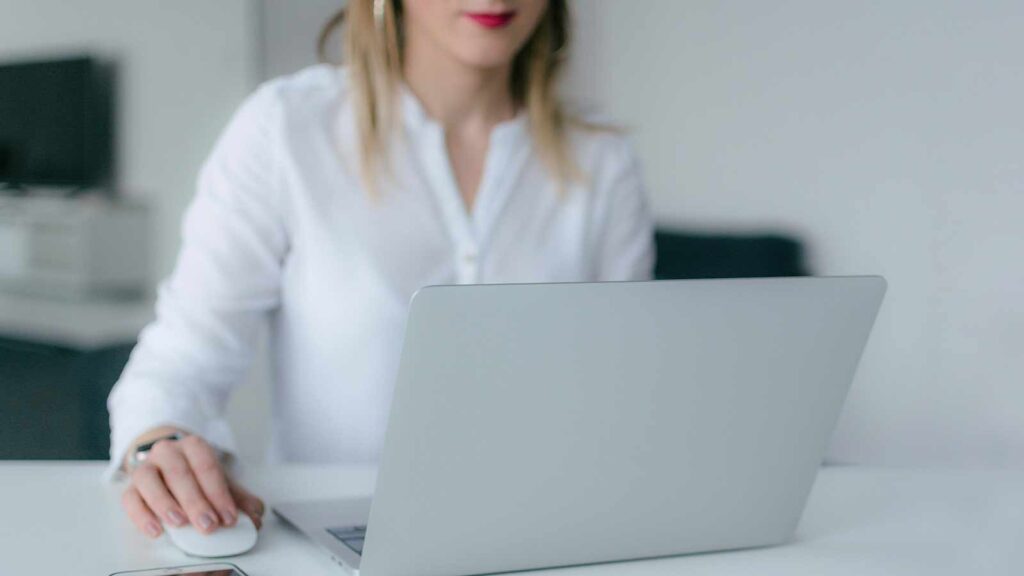 a woman sitting at a desk with a laptop looking up state of maine title search