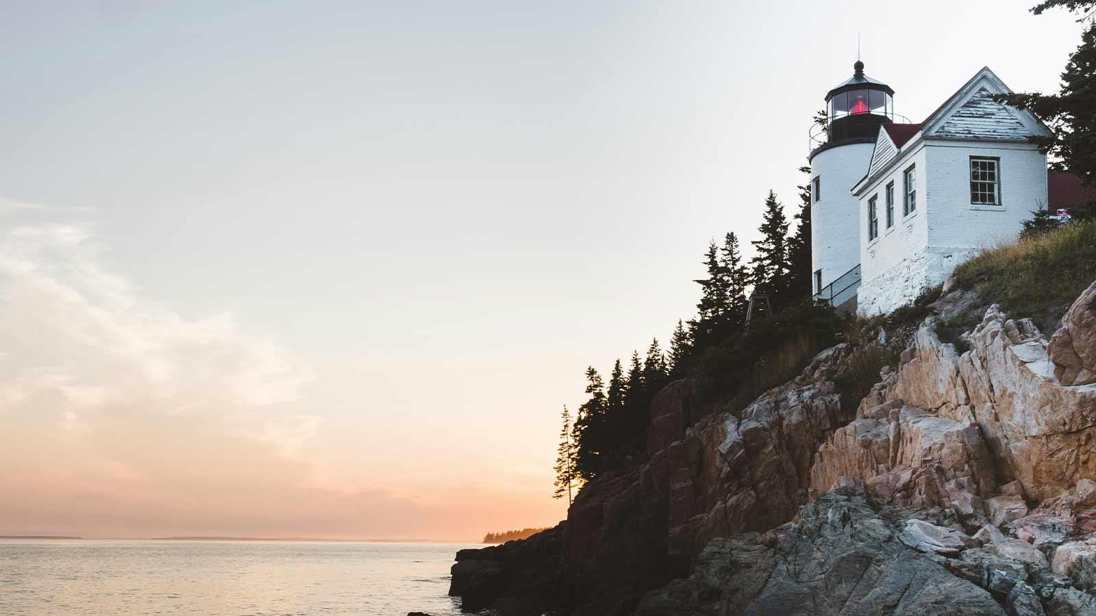 a lighthouse on a cliff by the water in portland maine, an example of Title Search in Maine
