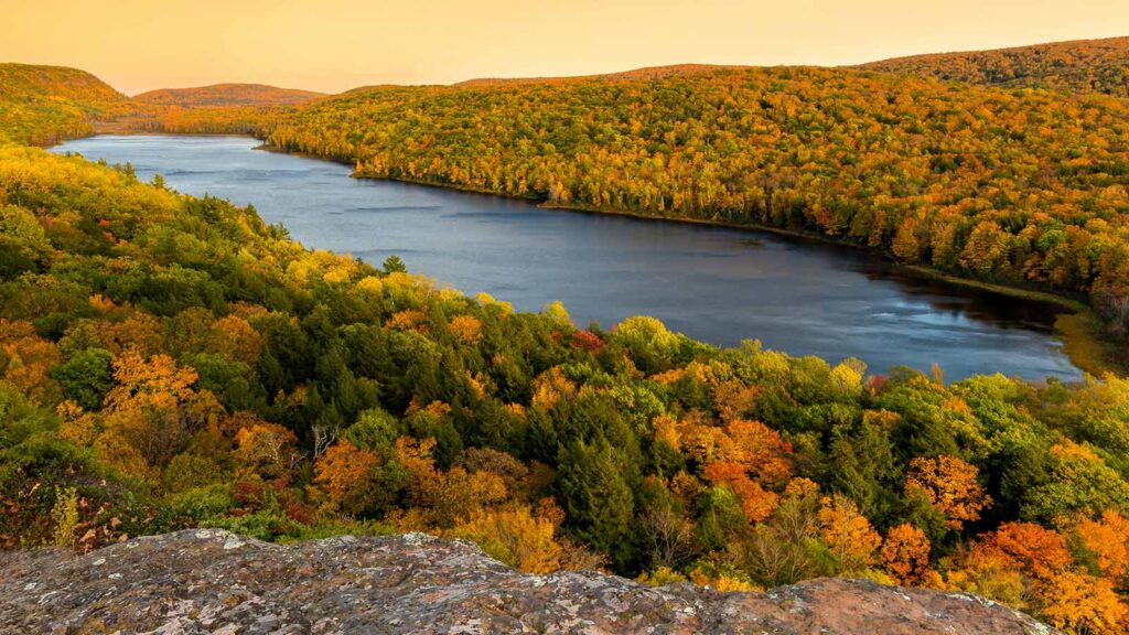 a river with trees and hills with Porcupine Mountains in the background how to do a title search in Michigan