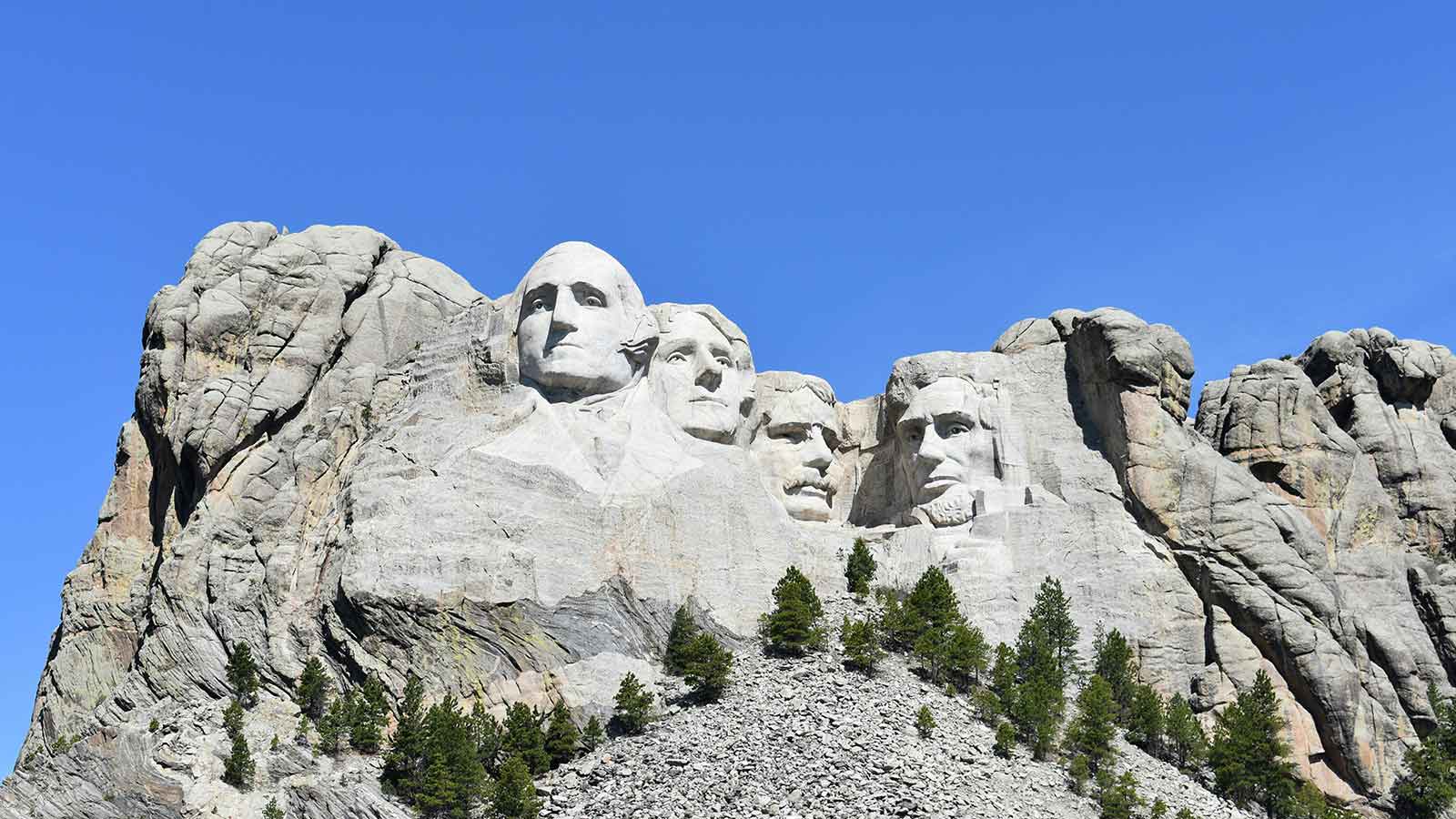 a large stone mountain with faces carved into it with Mount Rushmore National Memorial in the background symbolizing preliminary title report Title Search in South Dakota difference between title and deed title abstractor cloud on title lien release