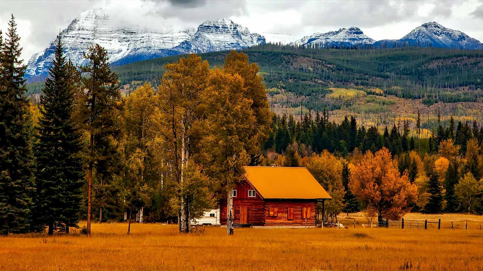 a house in a field with trees and mountains in the background title search in colorado