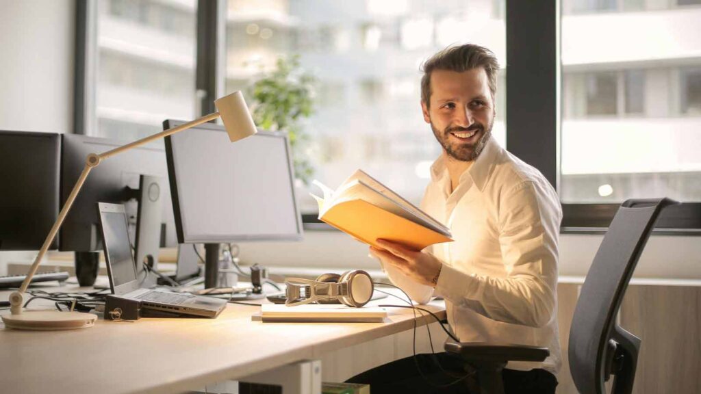 a man sitting at a desk holding a book West Virginia Title Searches & Deeds