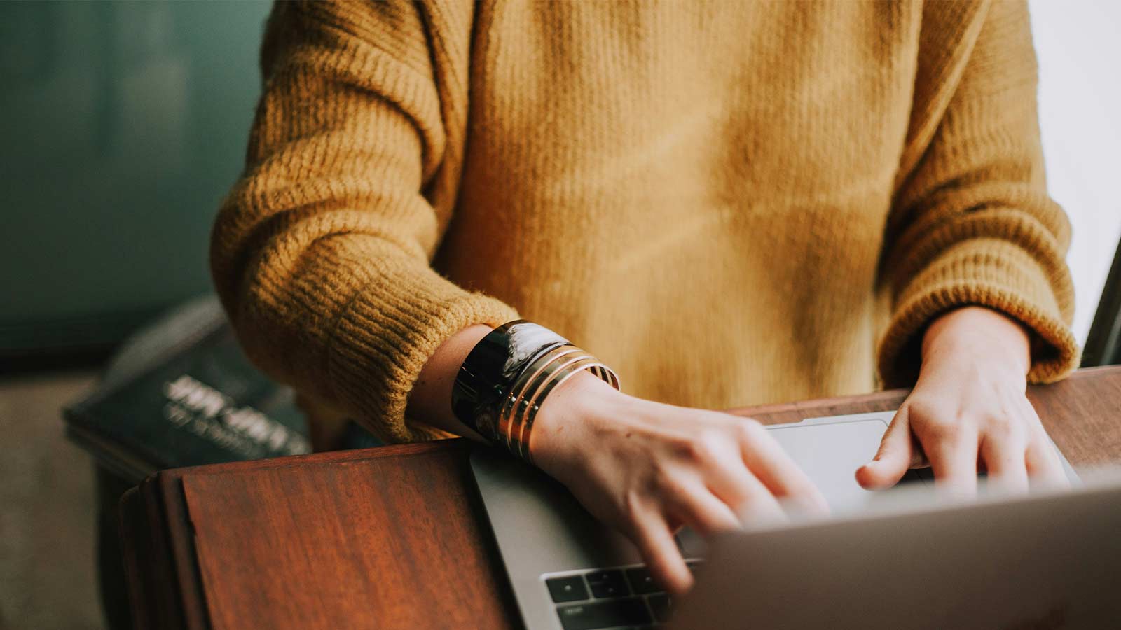 Person typing on laptop, wearing sweater. Nationwide Title Searches: 5 Key Coverage Gaps & Local Power