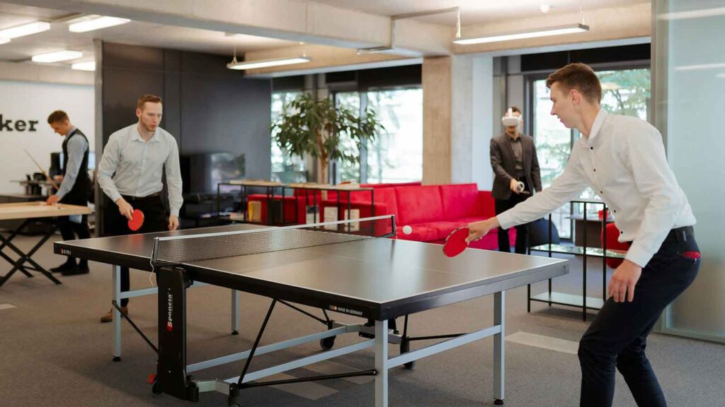 Two people playing table tennis indoors. tod deed