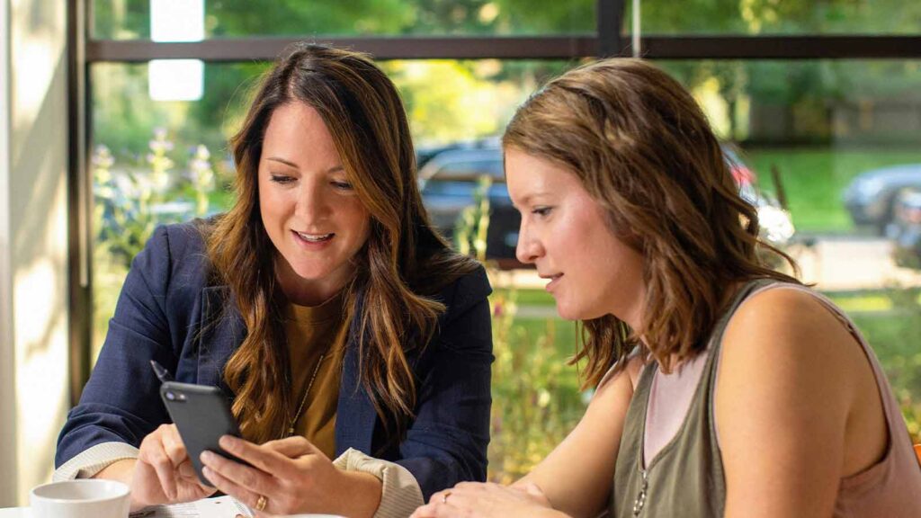 Two women discussing on a smartphone. AI title search in Wyoming